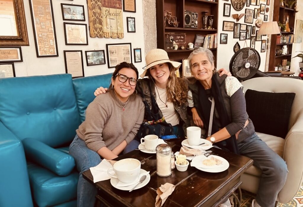 Three women sit together in a coffeehouse in Guatemala.